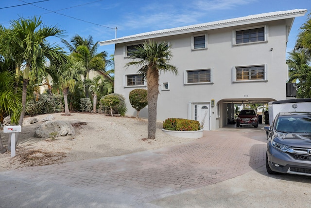 exterior space with decorative driveway, a carport, and stucco siding