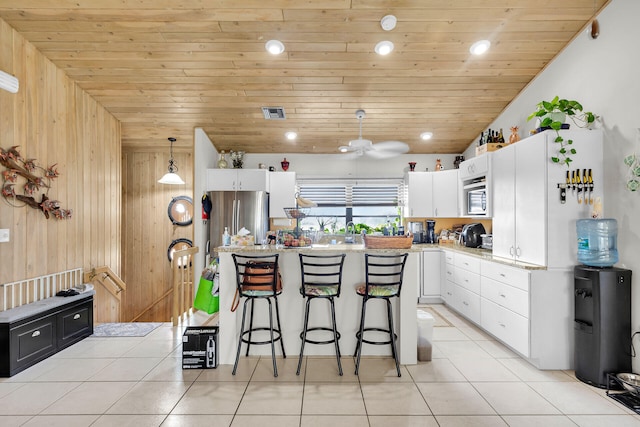 kitchen with wood ceiling, freestanding refrigerator, light countertops, a kitchen bar, and white cabinetry