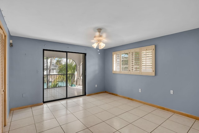 empty room featuring ceiling fan, light tile patterned floors, and baseboards