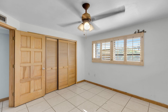 unfurnished bedroom featuring a closet, light tile patterned flooring, ceiling fan, and baseboards