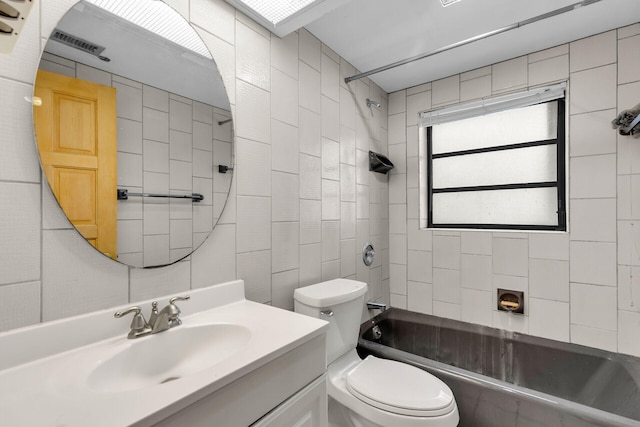 bathroom featuring visible vents, toilet, vanity, shower / washtub combination, and tile walls