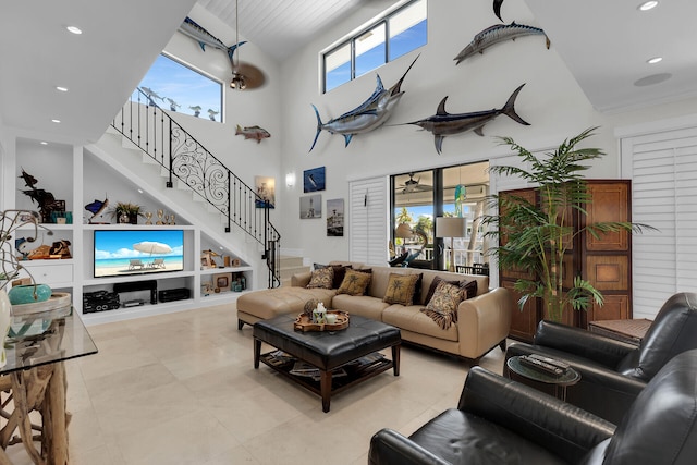 living room featuring built in shelves, plenty of natural light, and a towering ceiling