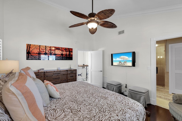 bedroom with ceiling fan, a towering ceiling, ornamental molding, and hardwood / wood-style floors