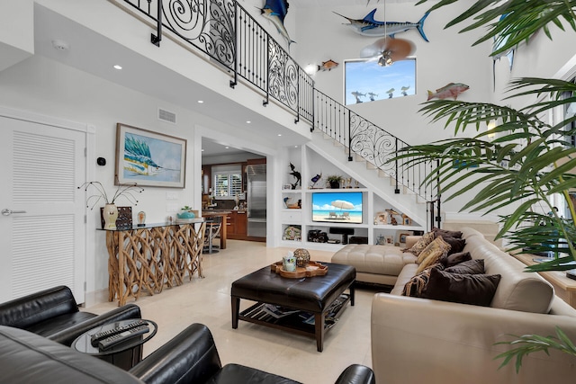 living room featuring light tile patterned flooring, a towering ceiling, and built in shelves