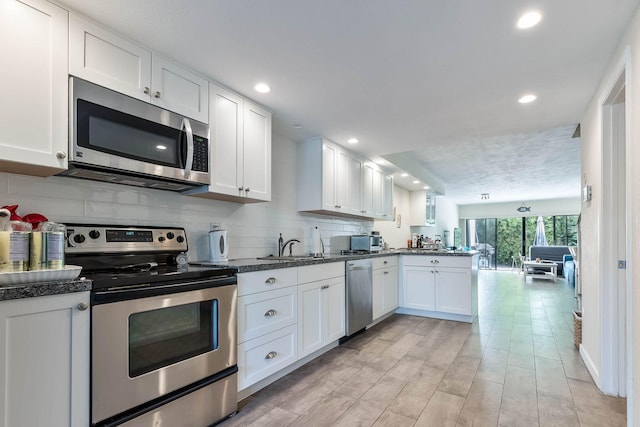 kitchen with sink, white cabinets, backsplash, stainless steel appliances, and light hardwood / wood-style flooring