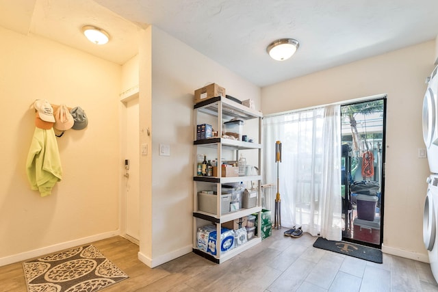 foyer with stacked washer / drying machine and light wood-type flooring