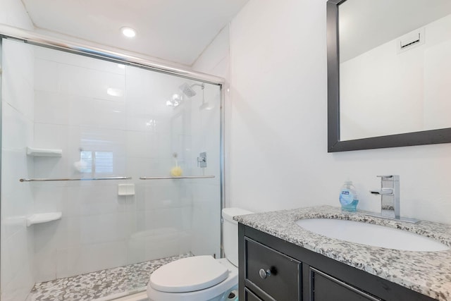 bathroom with walk in shower, vanity, and toilet