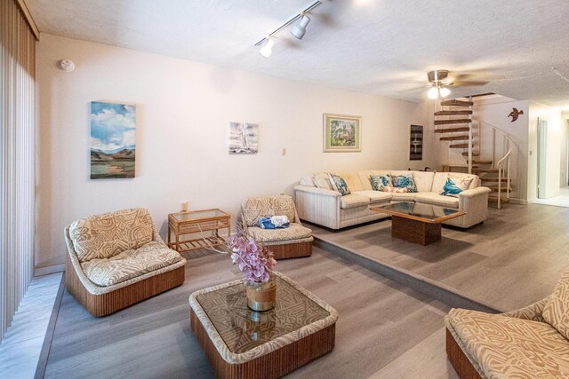 living room featuring ceiling fan, wood-type flooring, track lighting, and a textured ceiling