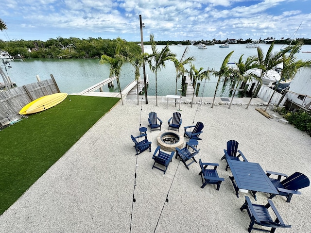 view of home's community with a patio, a water view, a dock, and an outdoor fire pit