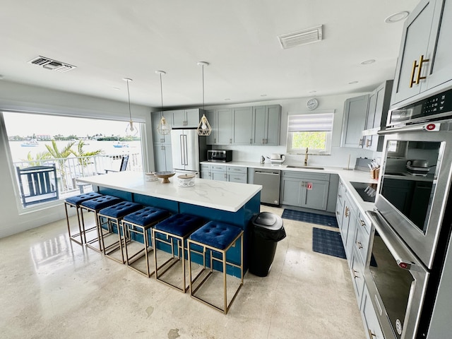 kitchen featuring stainless steel appliances, a center island, sink, and a kitchen bar