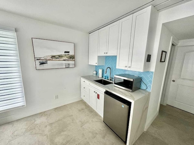 kitchen featuring tasteful backsplash, appliances with stainless steel finishes, sink, and white cabinets