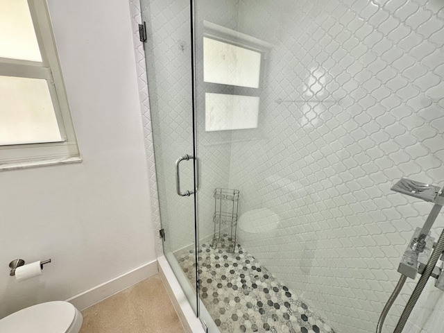 bathroom featuring a shower with shower door and toilet