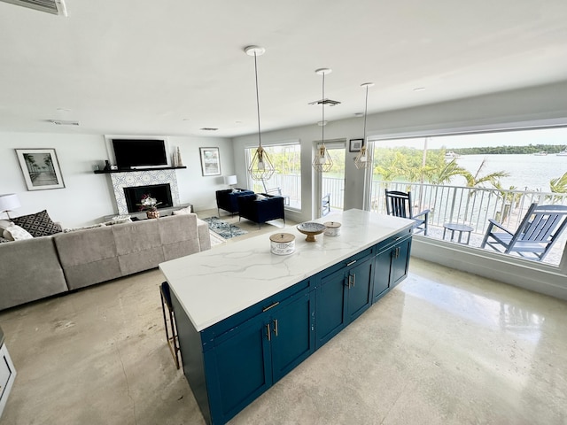 kitchen featuring pendant lighting, light stone counters, a center island, and blue cabinets