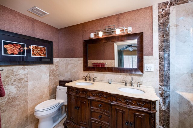 bathroom featuring vanity, tile walls, ceiling fan, and toilet