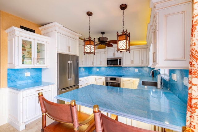 kitchen with sink, stainless steel appliances, decorative backsplash, decorative light fixtures, and kitchen peninsula