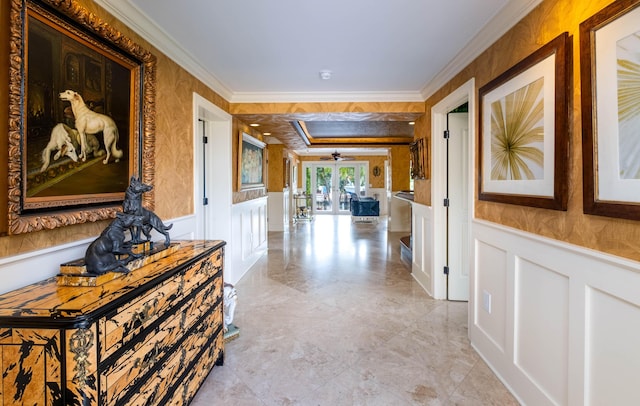 corridor with a wainscoted wall, wallpapered walls, ornamental molding, and a decorative wall