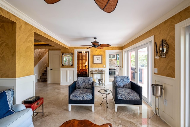 sitting room featuring wallpapered walls, wainscoting, stairs, crown molding, and a decorative wall