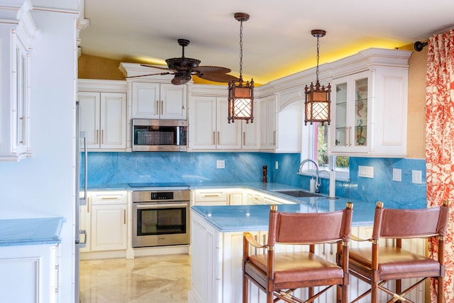 kitchen with a peninsula, appliances with stainless steel finishes, white cabinets, and a sink