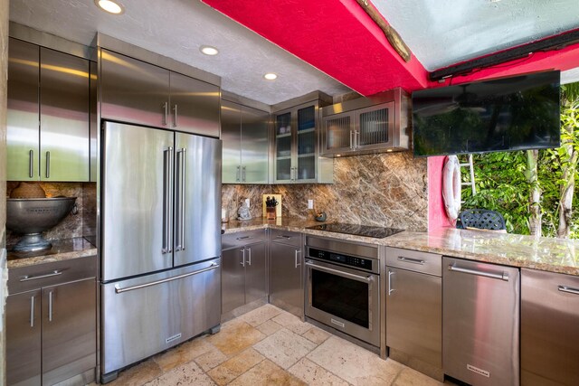 kitchen featuring decorative backsplash, stainless steel appliances, stone tile flooring, and recessed lighting