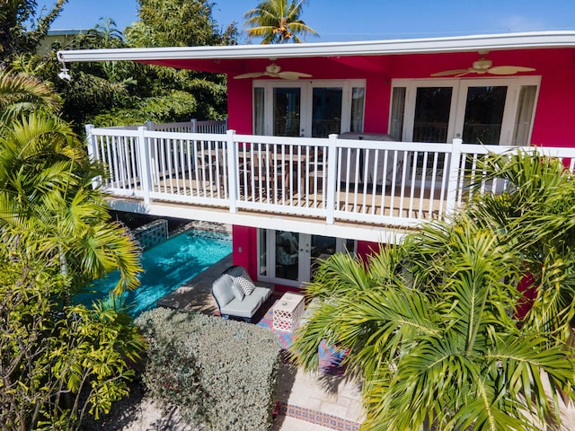 rear view of property featuring a balcony, ceiling fan, and french doors