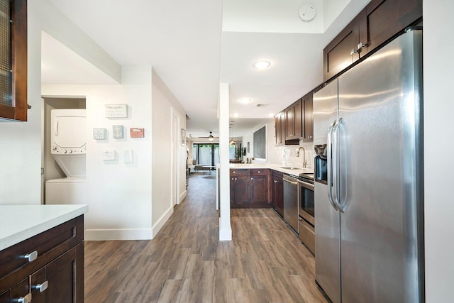 kitchen featuring dark wood-type flooring, dark brown cabinetry, sink, kitchen peninsula, and stainless steel appliances