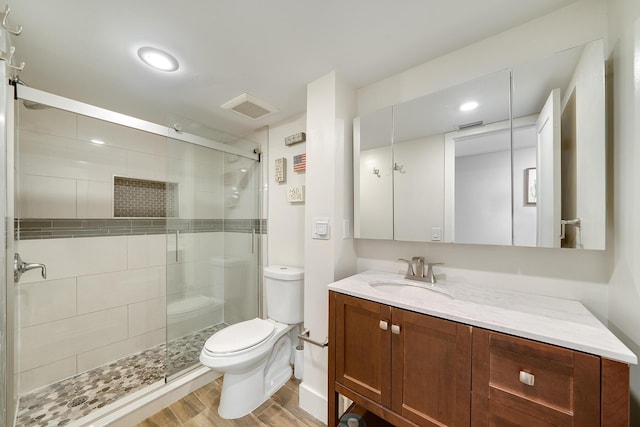 bathroom featuring hardwood / wood-style flooring, vanity, a shower with door, and toilet