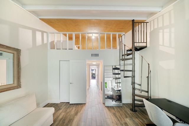 interior space with beamed ceiling, a towering ceiling, hardwood / wood-style floors, and wooden ceiling