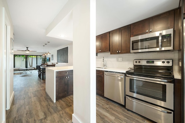 kitchen featuring pendant lighting, sink, decorative backsplash, dark brown cabinetry, and stainless steel appliances