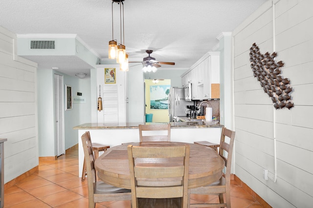 tiled dining space with crown molding, ceiling fan, and a textured ceiling