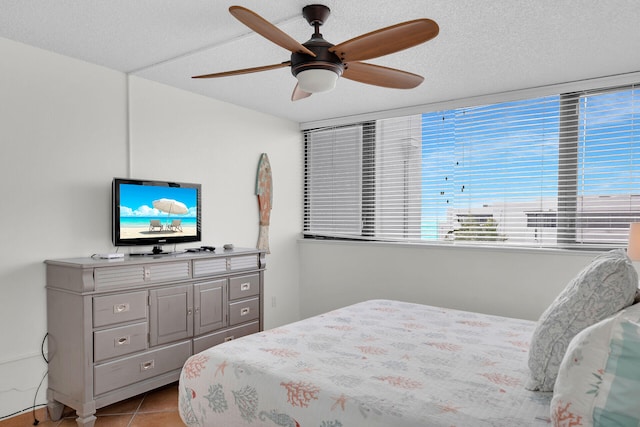 tiled bedroom with ceiling fan and a textured ceiling