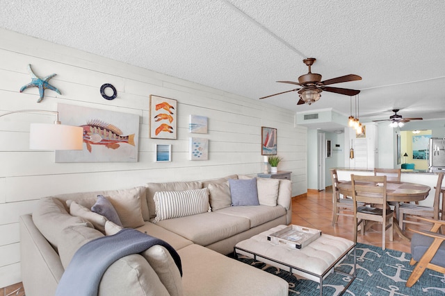 tiled living room featuring ceiling fan and a textured ceiling