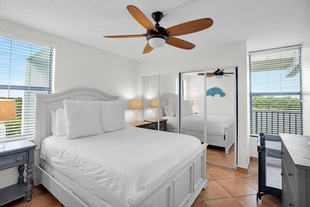 bedroom featuring ceiling fan, light tile patterned floors, a textured ceiling, and a closet