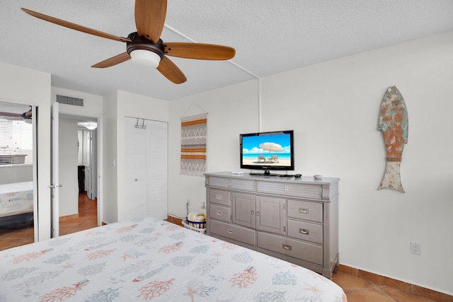 bedroom featuring ceiling fan, light tile patterned floors, a textured ceiling, and a closet