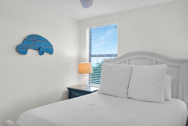 bedroom with ceiling fan and a textured ceiling