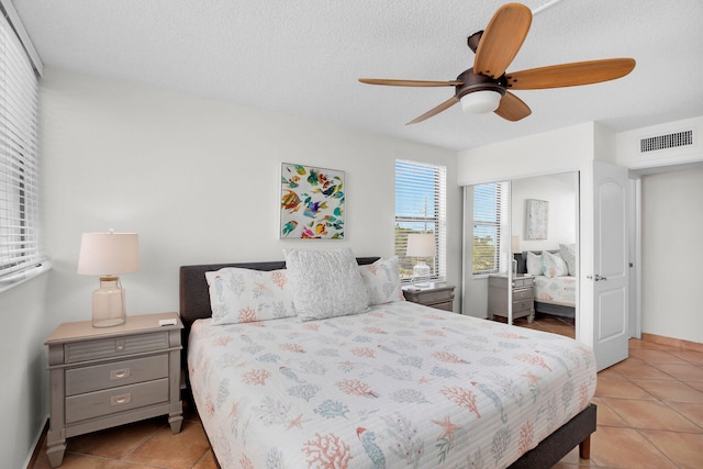 tiled bedroom featuring ceiling fan and a textured ceiling