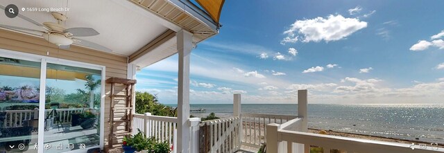 balcony with a view of the beach, ceiling fan, and a water view