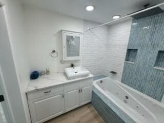 bathroom with tiled shower / bath, wood-type flooring, and vanity