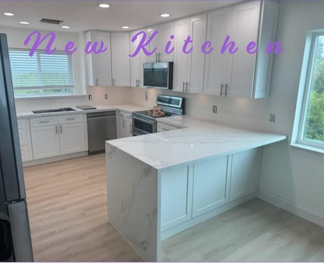 kitchen featuring stainless steel appliances, kitchen peninsula, and white cabinets