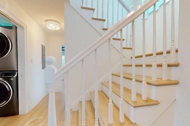 stairs featuring hardwood / wood-style flooring and stacked washer / drying machine