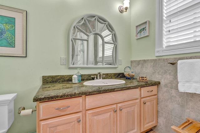 bathroom featuring vanity, toilet, and tile walls