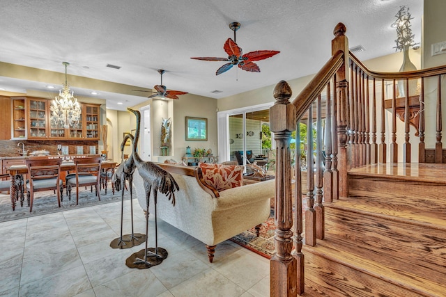 living room featuring ceiling fan with notable chandelier, a textured ceiling, and light tile patterned flooring