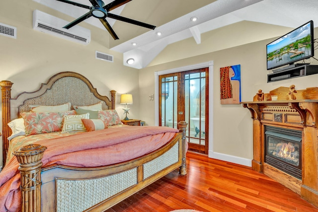 bedroom featuring an AC wall unit, vaulted ceiling with beams, hardwood / wood-style flooring, ceiling fan, and french doors