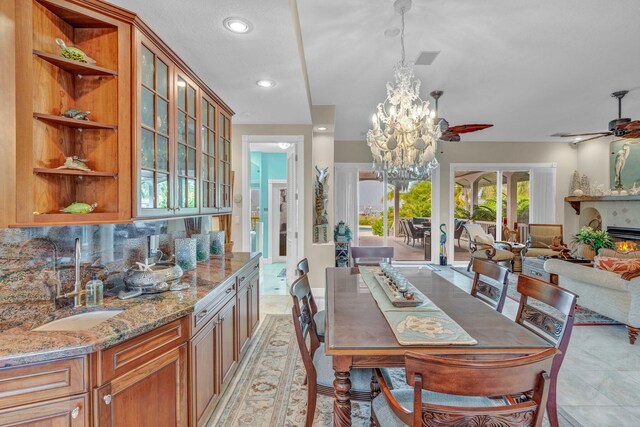 tiled dining area featuring ceiling fan with notable chandelier and sink