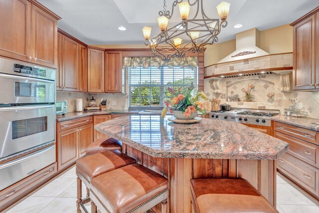 kitchen featuring pendant lighting, a breakfast bar, premium range hood, stainless steel appliances, and a center island