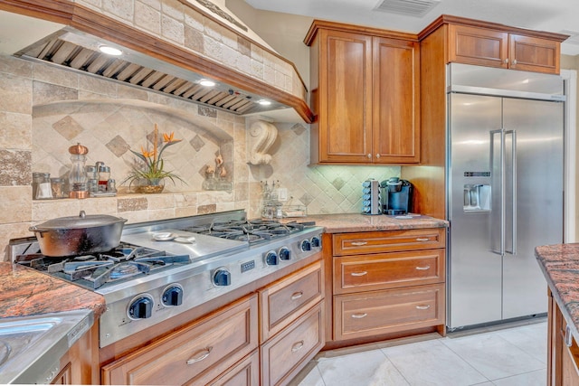 kitchen with premium range hood, stainless steel appliances, light stone countertops, and decorative backsplash