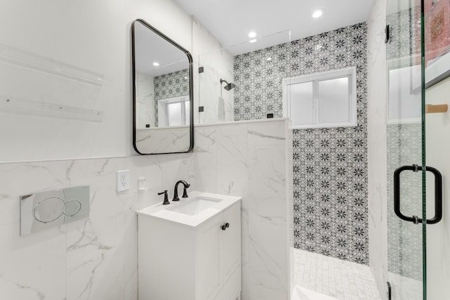 bathroom featuring vanity, a shower with shower door, and tile walls