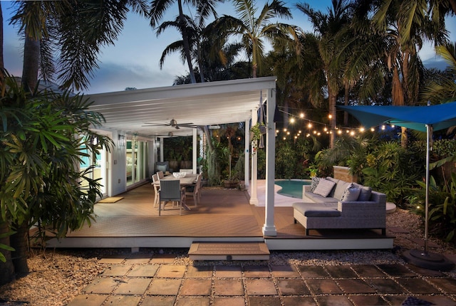 patio terrace at dusk featuring a pool side deck, ceiling fan, and outdoor lounge area