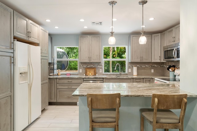 217 Gasparilla Dr, Key Largo, FL 33037 - kitchen with stainless steel appliances, a peninsula, tasteful backsplash, a breakfast bar, and light stone countertops