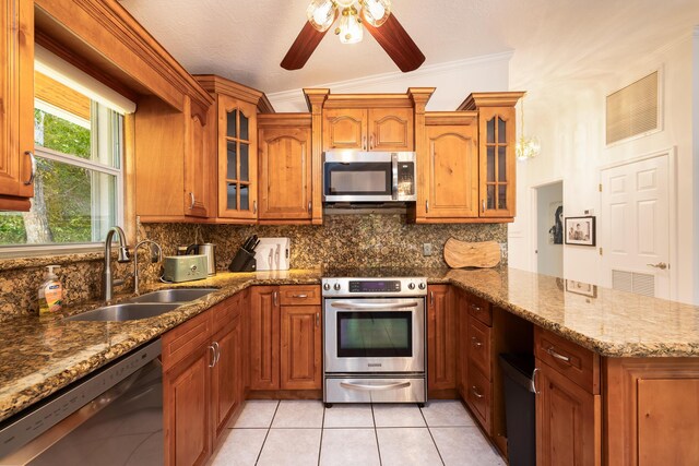 kitchen featuring sink, light tile patterned floors, appliances with stainless steel finishes, backsplash, and light stone counters