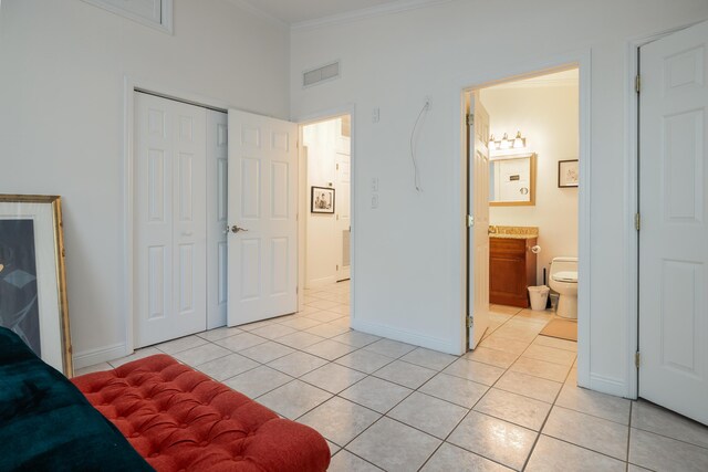 bedroom with ensuite bathroom, ornamental molding, a closet, and light tile patterned flooring